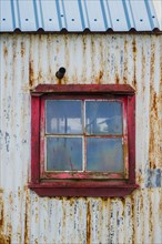 Rusty, weathered corrugated iron facade with window