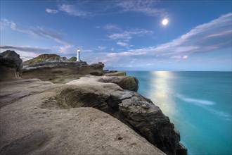 Lighthouse at full moon on the cliffs of lava rock at Castlepoint, Masterton