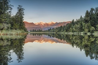 Snowy mountain peaks of Mount Cook and Mount Tasman reflected in Lake Matheson in the evening light, Westland National Park