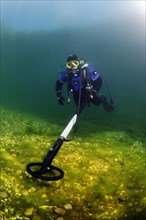 Diver in dry suit with metal detector searches the lake bottom for metal objects, Echinger Weiher