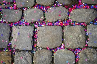 Confetti after a carnival parade between cobblestone pavement, carnival