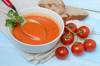 Tomato soup with spoon in bowl, tomatoes
