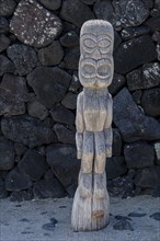 Wooden guardian figure Tiki in front of lava stone wall, Pu'uhonua O Honaunau National Historical Park
