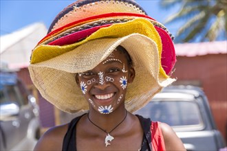 Local saleswoman with traditional face painting sells sun hats, Diego Suarez