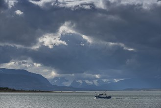 Fishing boat in the bay of last hope with dark clouds, Fjordo Ultima Esperanza