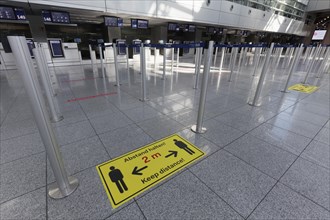 Sign with distance rule in front of the deserted baggage check, flight ban due to corona pandemic