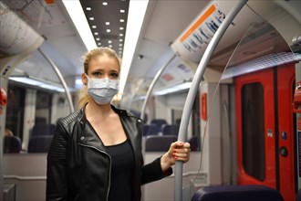 Woman with face mask, standing in suburban train