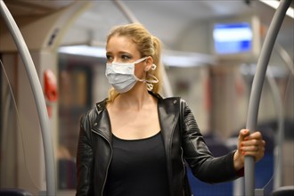 Woman with face mask, standing in suburban train