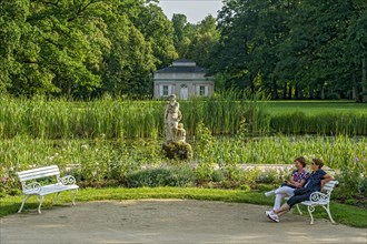 Two woman on benches, pond with sculpture of Venus