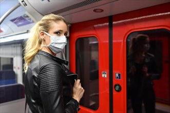 Woman with face mask, standing in suburban train
