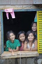 Happy children looking out of the window of their house