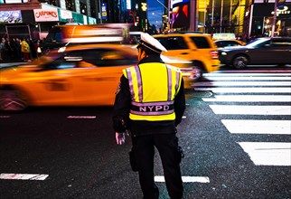 Policeman with NYPD vest monitors heavy taxi traffic in Times Square