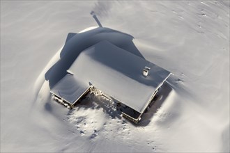Snow-covered mountain hut in winter from above