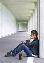 Teenager sitting with beer in an underpass and smoking