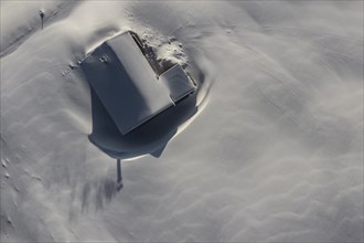 Snow-covered mountain hut in winter from above