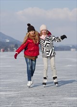 Young happy girls ice skating at a lake