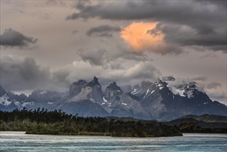 View over the river Rio Serrano to the mountain range Cuernos del Paine with cloudy sky