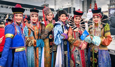 Beautiful young ladies staying in Mongolian traditional costumes of different ethnic groups in the central square