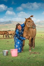 Mongolian nomadic woman petting the horse