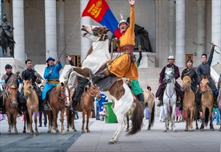 Young horse rider man a rising horse in front of the Parliament house during NAADAM festival