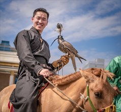 Young hunter with trained falcon on the horse