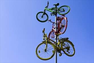 Colourful bicycles hanging from a flagpole