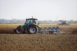 Tractors plough a dry field