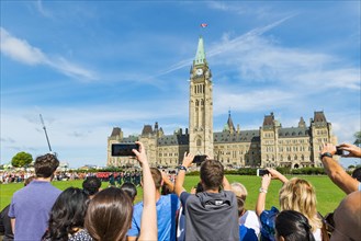 Visitors photograph the changing of the guard in front of the Canadian Parliament Building Centre Block