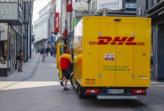 DHL parcel trolleys in the pedestrian zone in front of shops and stores