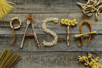 Word pasta from different noodles on wooden table