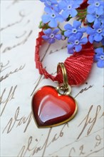 Pendant with heart and forget-me-not on letter paper with old writing