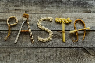 Word pasta from different noodles on wooden table