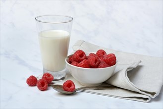 Bowl with raspberries and glass of milk