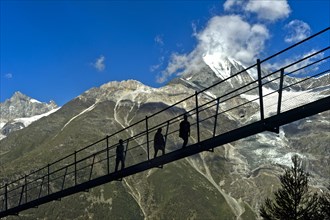 Hikers in the back light on the Charles Kuonen suspension bridge