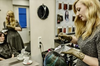 Hairdresser in a hairdressing salon dying strands of hair with aluminium foil