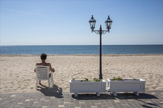 Tourist sitting in a chair on a lonely sandy beach