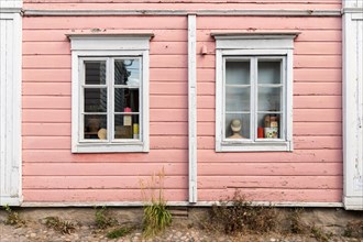 Pink painted wooden house facade with two windows