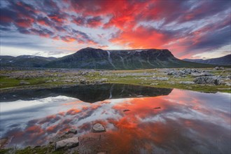 Mountain range reflected in the lake in evening mood with red clouds