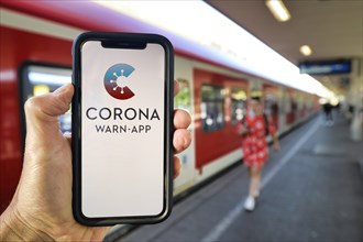 Hand holding smartphone with Corona Warn-APP on the platform