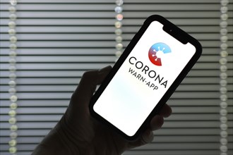 Hand holds smartphone with Corona Warn-APP