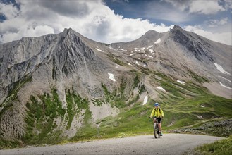 Mountain biker rides on alpine gravel road
