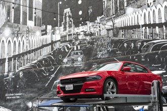 Red Dodge sports car in front of mural