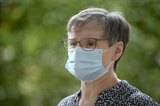 Elderly woman wears mouth mask correctly over nose and mouth