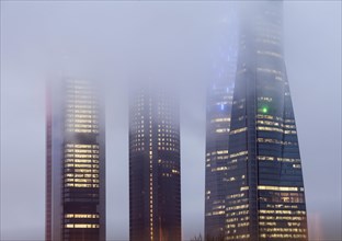 Cuatro Torres Business Area Office building illuminated in evening fog