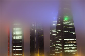 Cuatro Torres Business Area Office building illuminated in evening fog