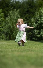 Girl in Dirndl runs across a meadow