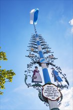 Maypole with group of figures and waving Bavarian flag