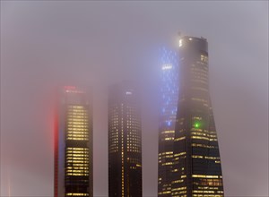 Cuatro Torres Business Area Office building illuminated in evening fog