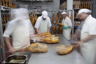 Employees select pieces from Jamon Serrano for packaging