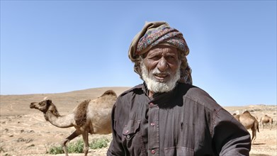 Camel breeder with camels in the mountains north of Salalah